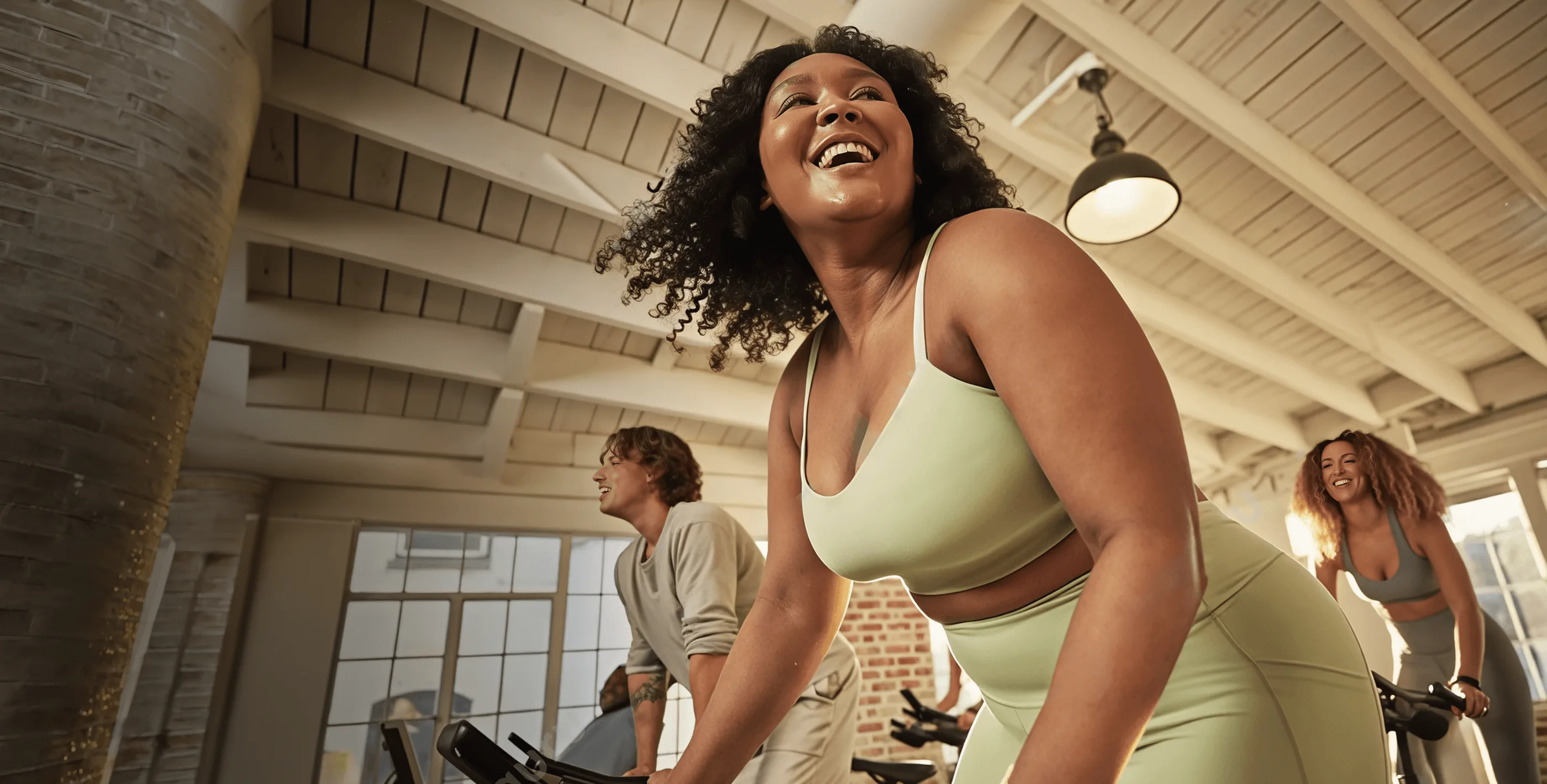 Adults training together on stationary bikes in a sunlit studio